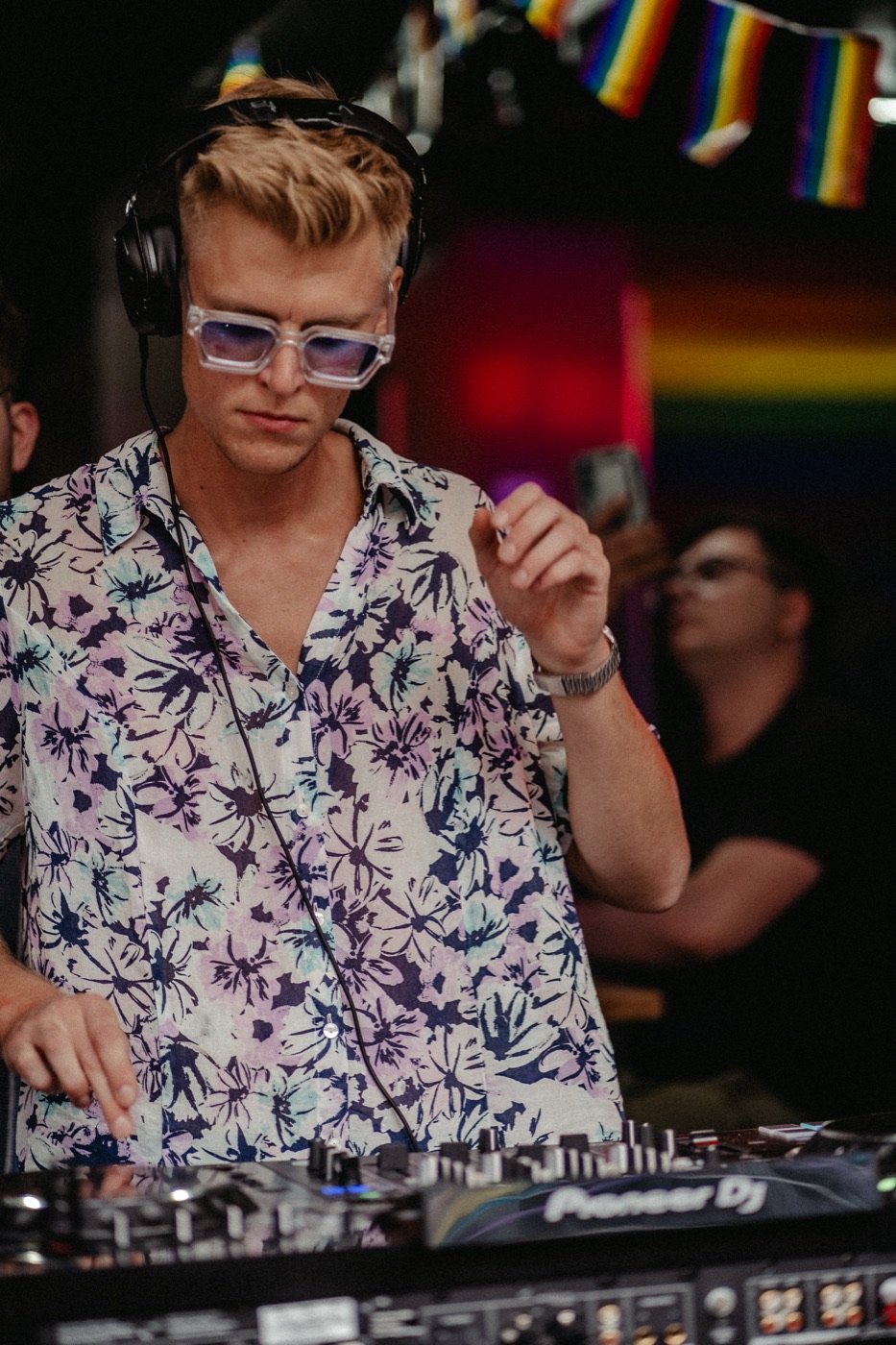 DJ Tim Matthiä auflegend vor Regenbogenflaggen beim Christopher Street Day
