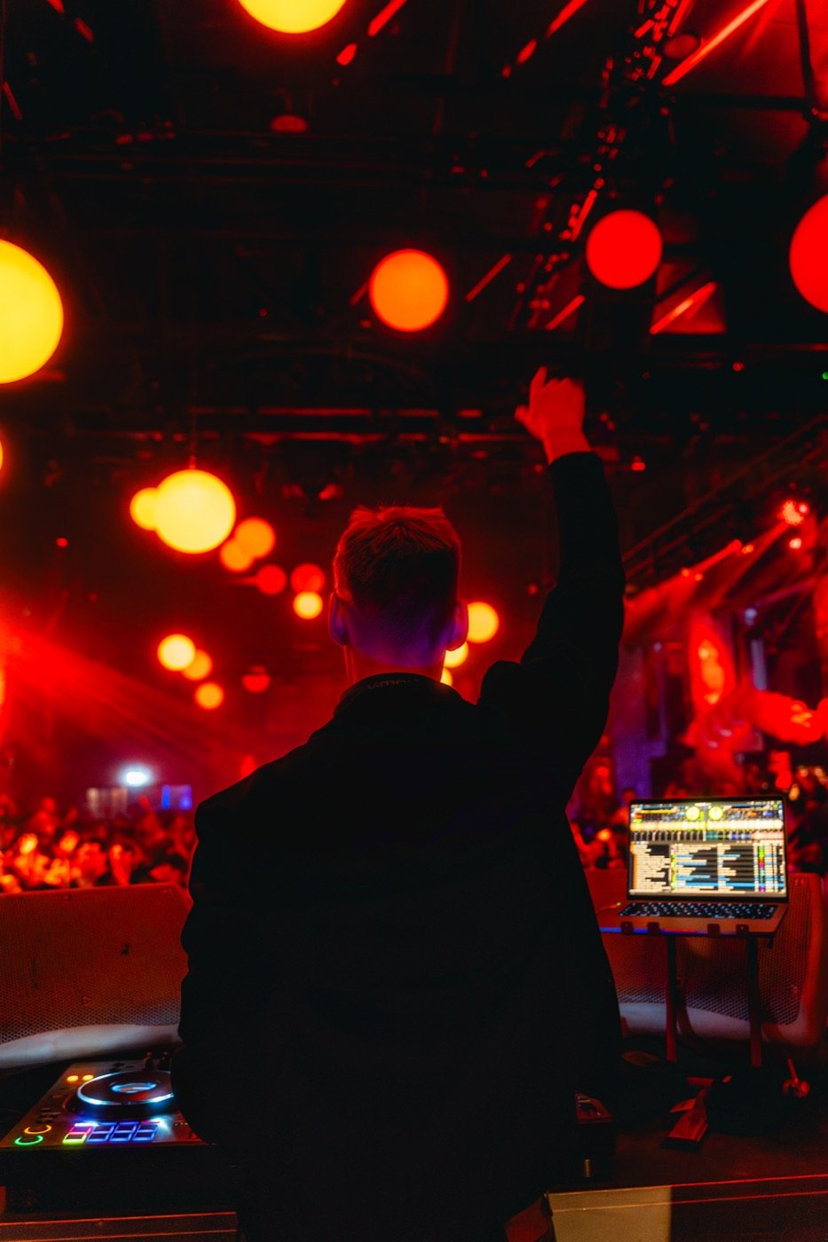 DJ Tim Matthiä mit erhobenem Arm vor tanzender Menschenmenge